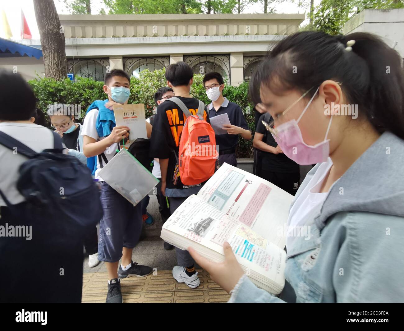 Die Studenten überprüfen Bücher vor dem Betreten des Testzentrums für die Prüfungen am letzten Tag des 2020 National College Eingang, auch bekannt als Gaokao, Nanjin Stockfoto