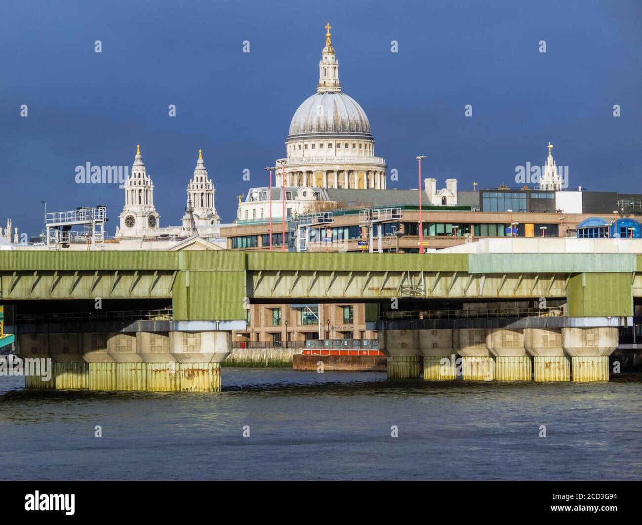 Blick vom Südufer der Themse St Paul's Cathedral und seine ikonische Kuppel hinter der Cannon Street Eisenbahnbrücke an einem Wintermorgen Stockfoto