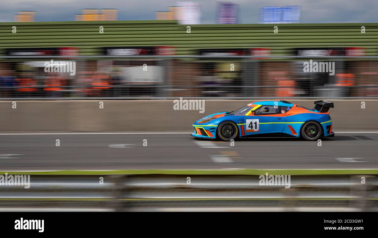 Eine Schwenkaufnahme eines blauen und orangenen Rennwagens, der eine Strecke fährt. Stockfoto
