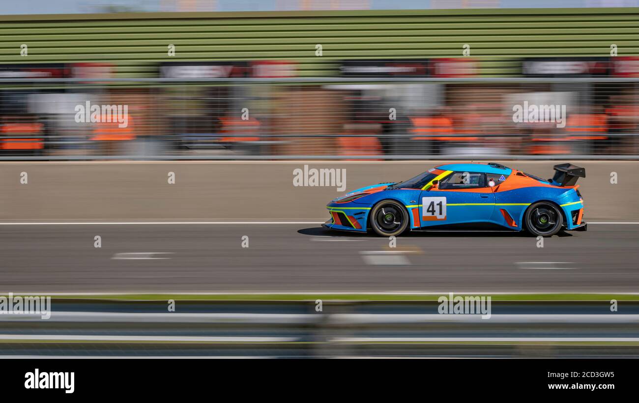 Eine Schwenkaufnahme eines blauen und orangenen Rennwagens, der eine Strecke fährt. Stockfoto