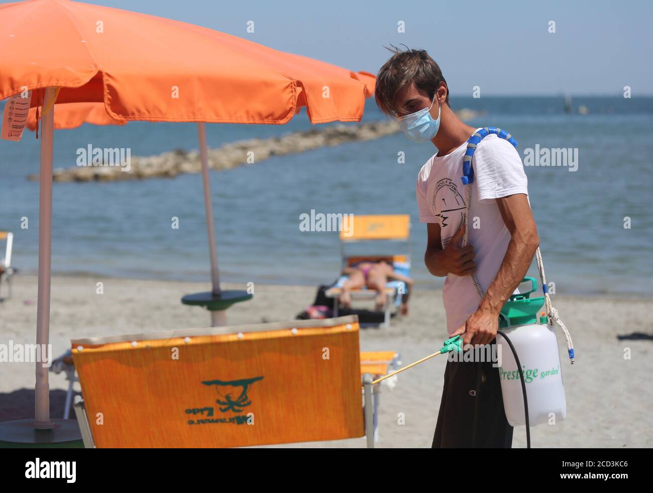 Rimini, Italien. Juli 2020. Ein junger Mann desinfiziert einen Stuhl während der Covid-19 Pandemie, en Punta Marina di Ravenna, Italien. Quelle: Cesar Luis de Luca/dpa - ACHTUNG: Nur für redaktionelle Verwendung im Zusammenhang mit der aktuellen Berichterstattung und nur mit vollständiger Erwähnung der oben genannten Credit/dpa/Alamy Live News Stockfoto