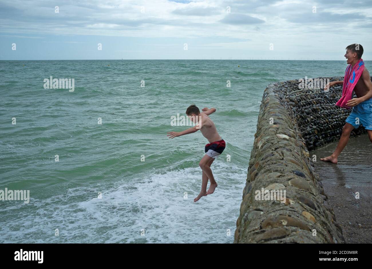 Ein Teenager gräbe Steine ins Meer in Brighton Stockfoto