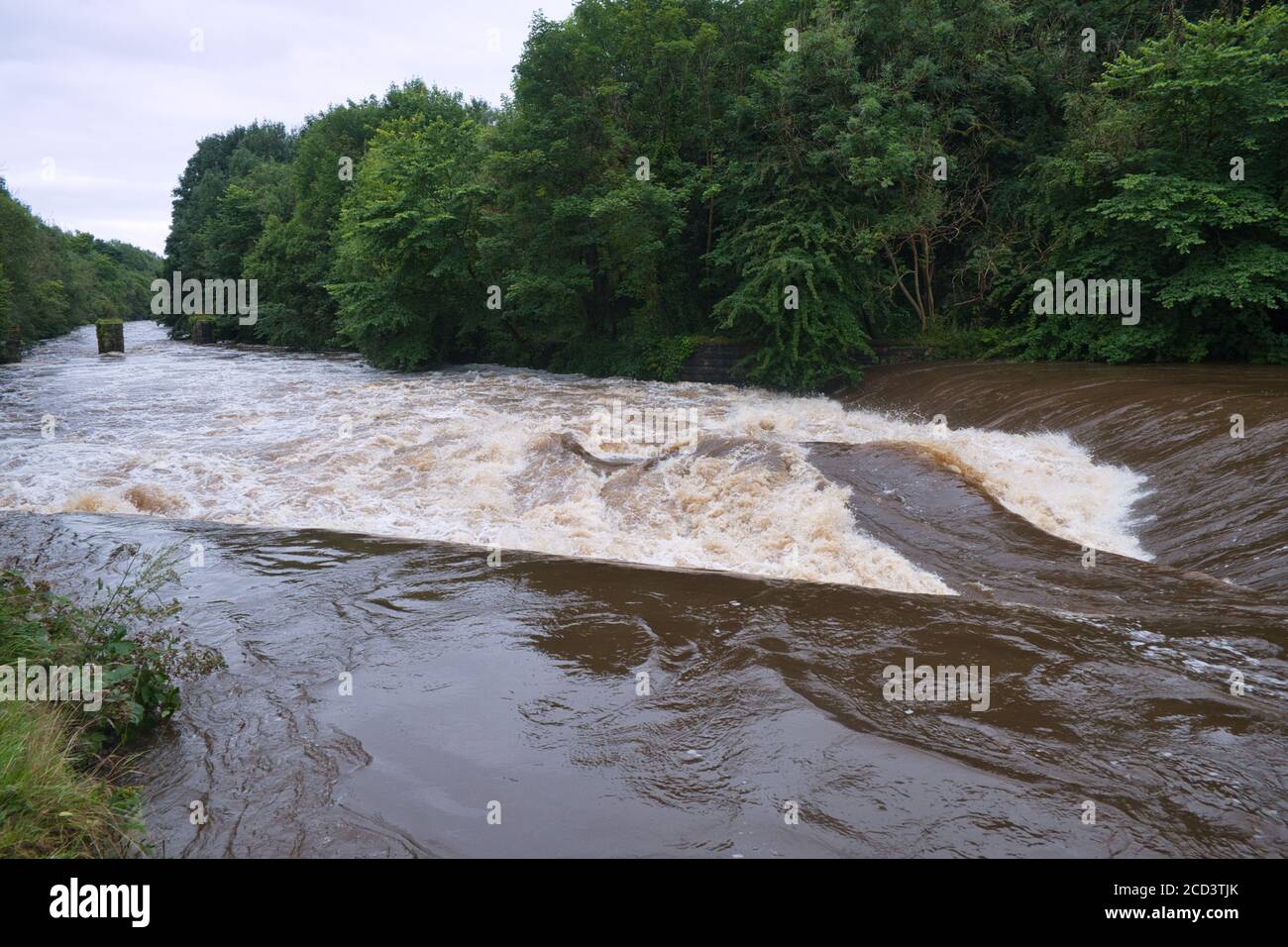 Der Fluss Kelvin in Glasgow, in Spaten, Wasser fließt in voller Kraft über das Wehr. Stockfoto