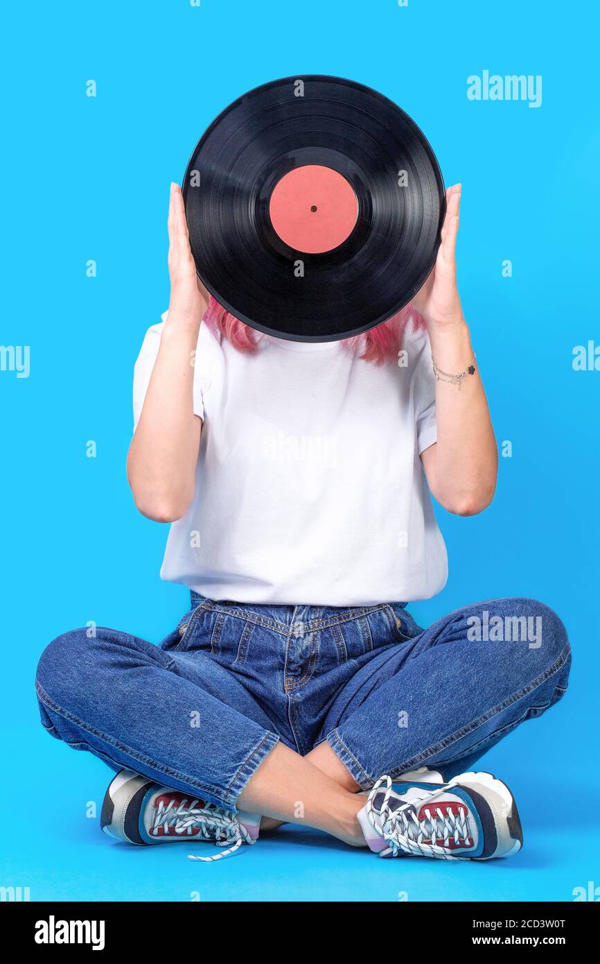 Frau dj-Portrait mit Vinyl-Platte vor blauem Hintergrund. Retro-Bild von Frau mit Vinyl-Schallplatte Stockfoto