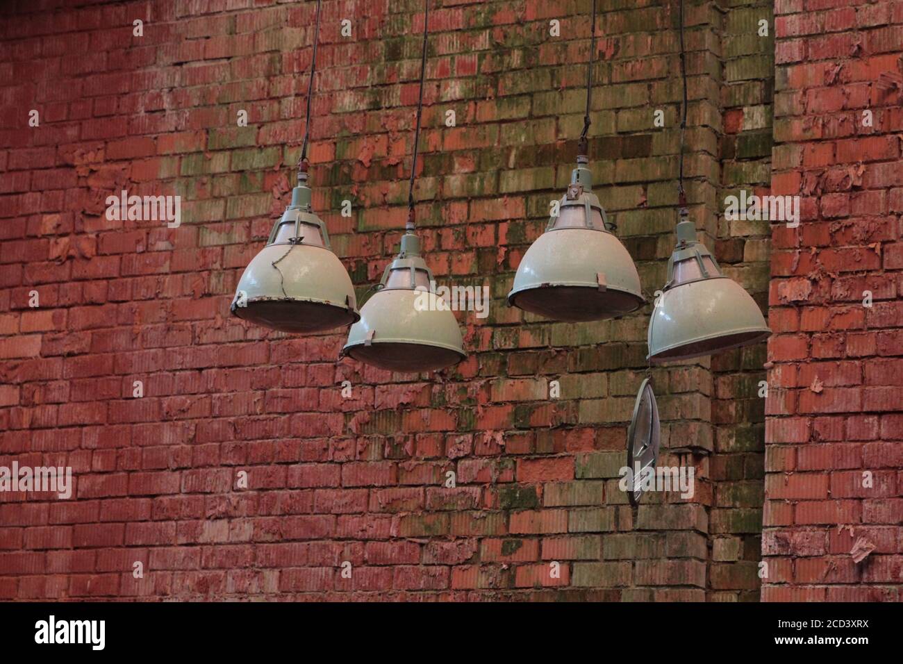Vier alte kaputte Deckenlampen vor einem roten Ziegelwand Stockfoto