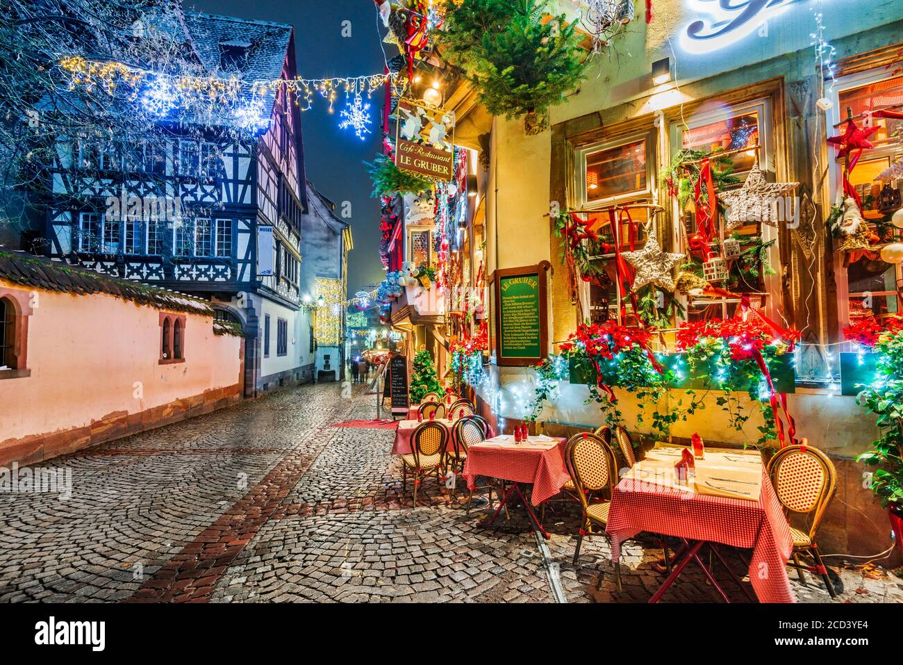 Straßburg, Frankreich. Straßencafé-Tische in der Winterstraße, Weihnachtszeit. Elsass Nacht Szene mit hervorgehoben alten Gebäuden in tourisitic Konzept. Stockfoto