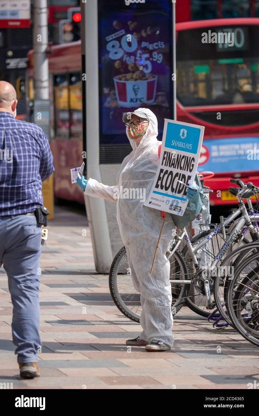 London, Großbritannien. August 2020. Extinction Rebellion Mitglied, in einem sauberen Anzug gekleidet, gibt gefälschtes Geld außerhalb Clapham Junction Bahnhof (gegenüber Barclays Bank). XR setzt ihre „Harklays“-Kampagne fort und untersucht die Barclays Bank wegen Verbrechen gegen die Menschlichkeit und den Planeten. XR stellt fest, dass Barclays heute der größte europäische Investor in fossile Brennstoffe ist. Quelle: Neil Atkinson/Alamy Live News Stockfoto