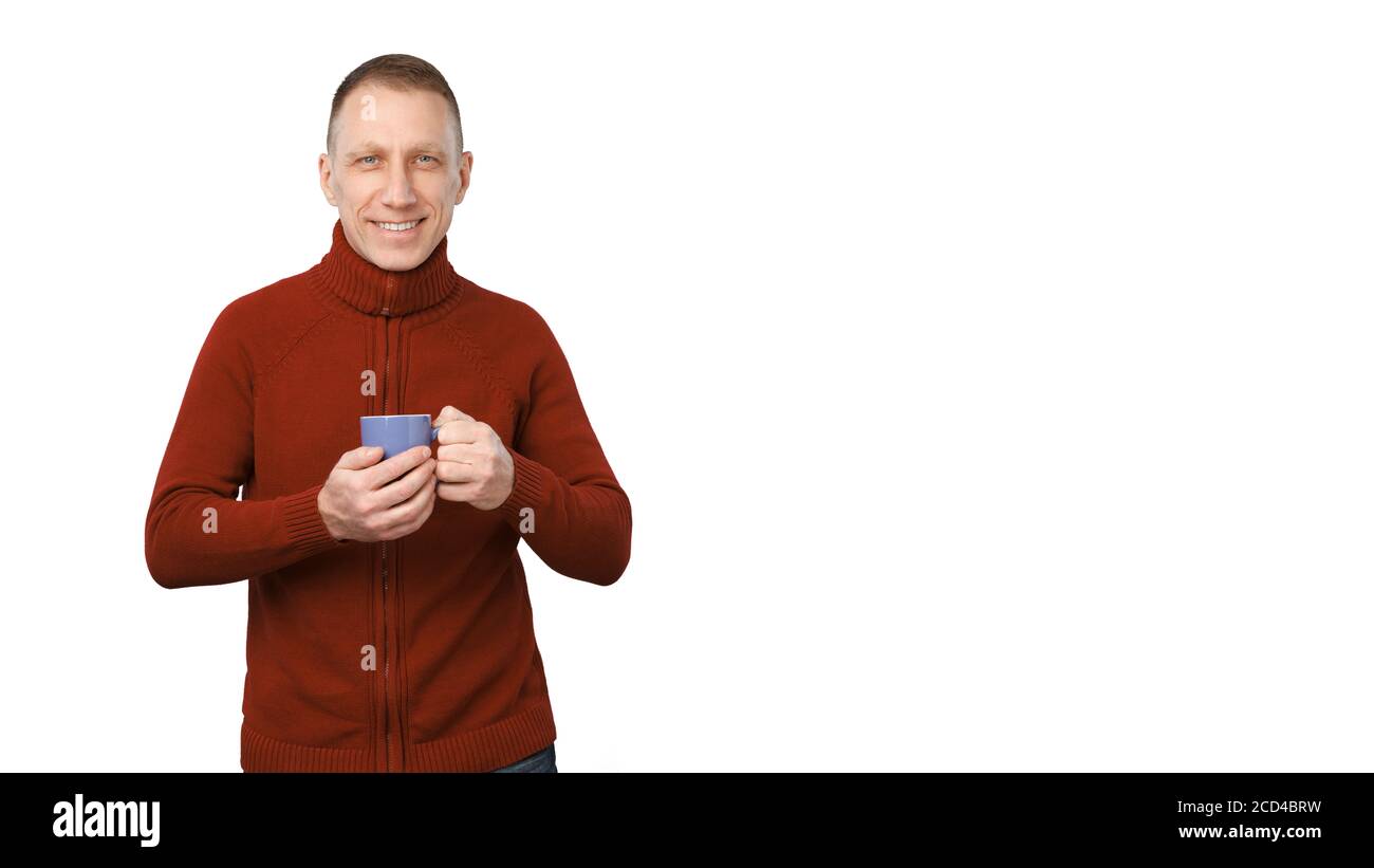 Lächelnder Durchschnittsalter Mann in roten Pullover isoliert auf weißem Hintergrund hält eine blaue Tasse Kaffee. Stockfoto