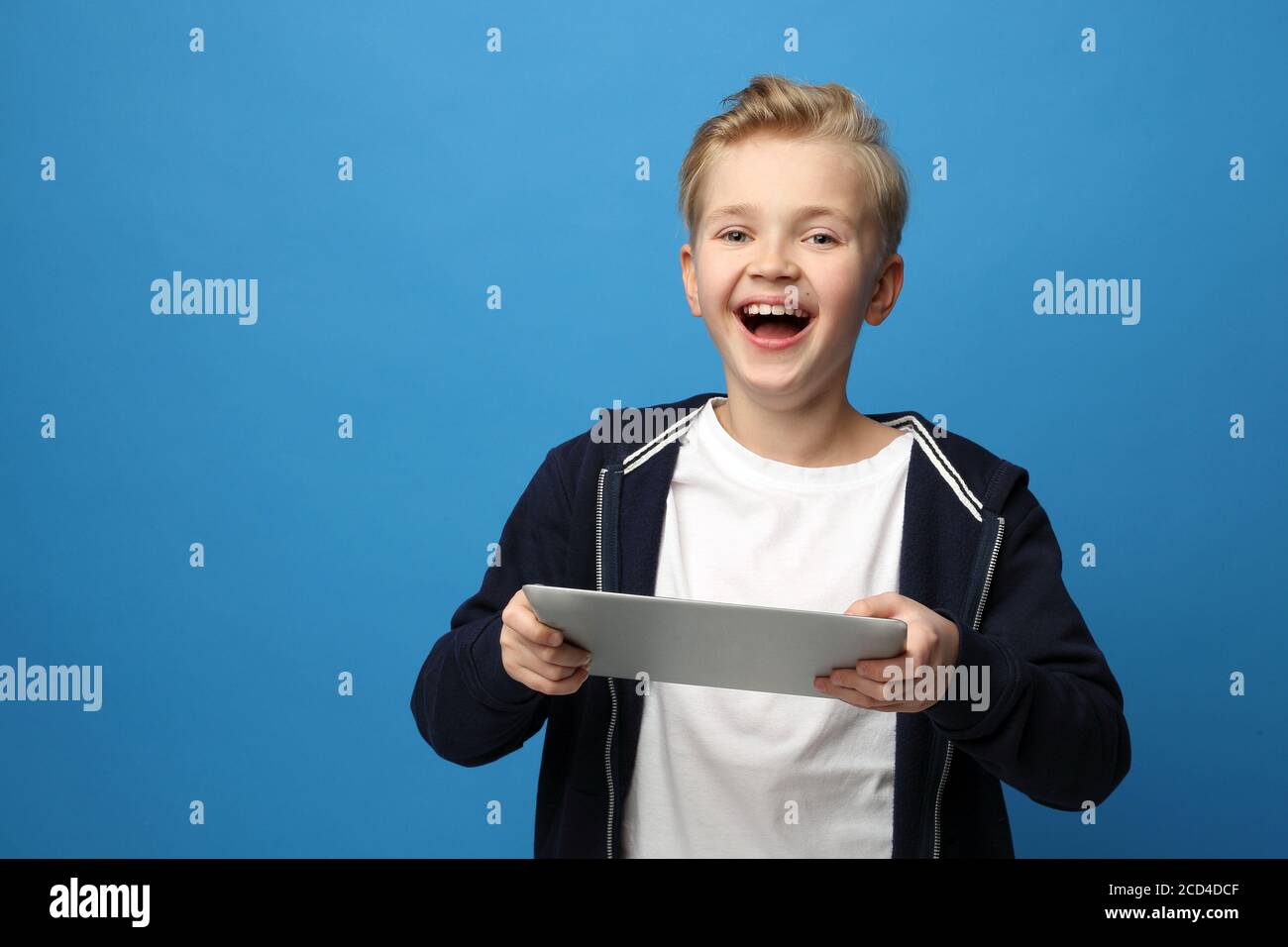 Überrascht Kind Gesicht, Emotionen. Der überraschte Junge sieht auf dem Tablet. Ein Kind mit einem Tablet. Lächelnder Junge mit einem Tablet. Porträt eines Kindes auf einem Stockfoto