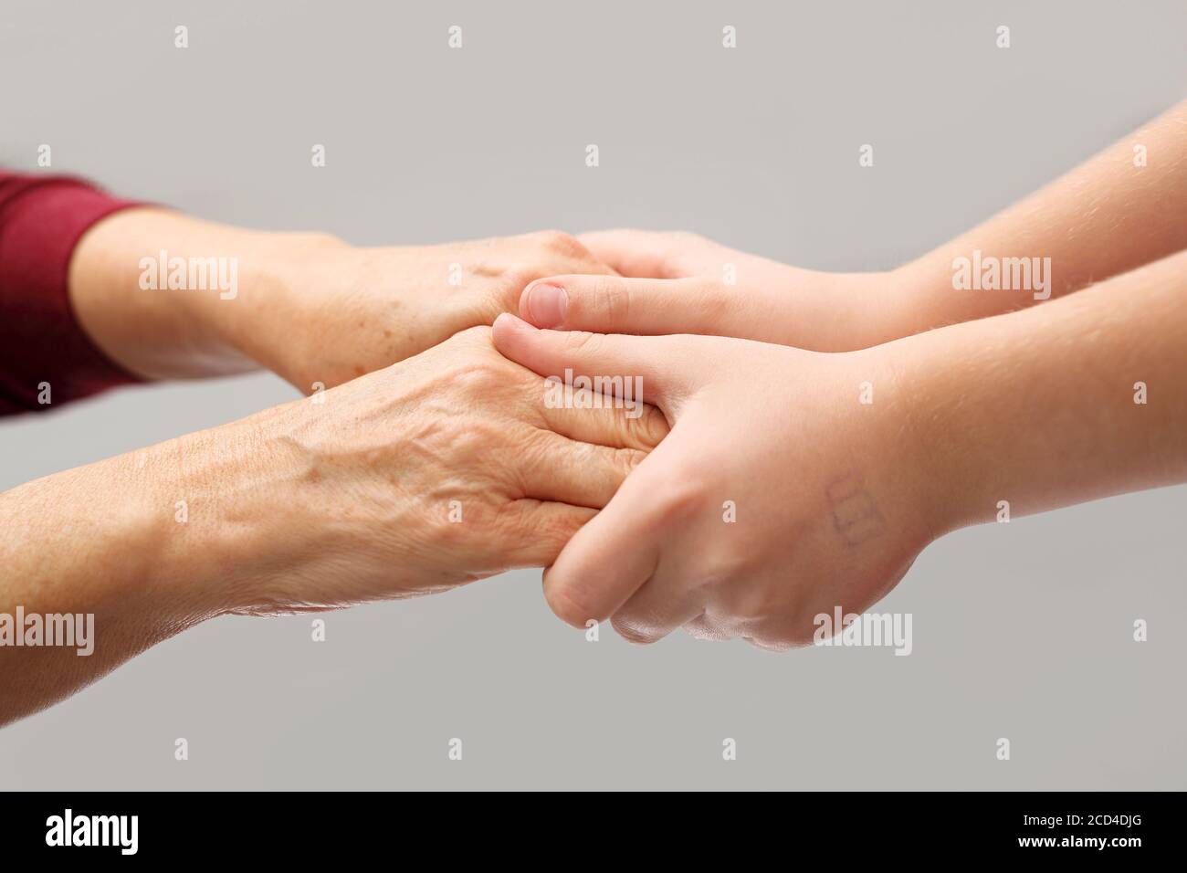 Pflege eines älteren Menschen. Eine helfende Hand. Die alten und jungen Hände halten in einer Geste der Fürsorge. Stockfoto