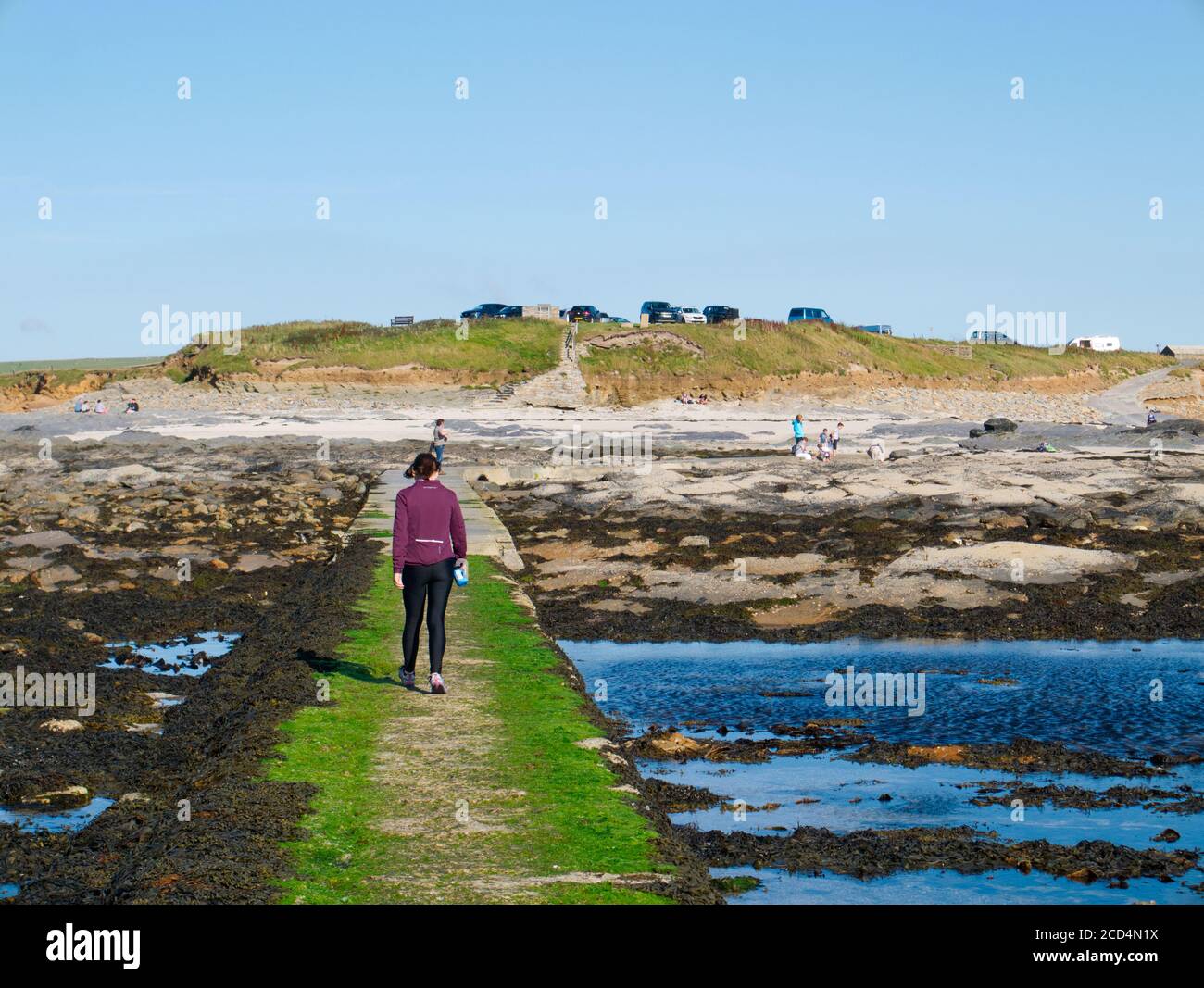 Frau, die bei Ebbe über den Brough of Birsay Causeway, Orkney Islands, geht Stockfoto