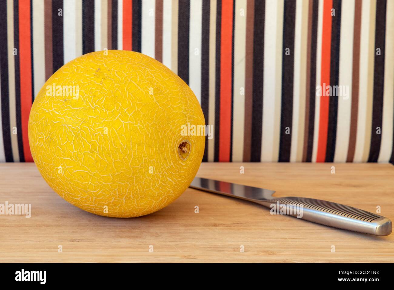 Ganze Honigmelone auf einem Holzbrett mit einem Messer von ihm bereit, serviert werden positioniert, köstliche Sommerfrucht reich an Nährstoffen, gut für Sie Stockfoto