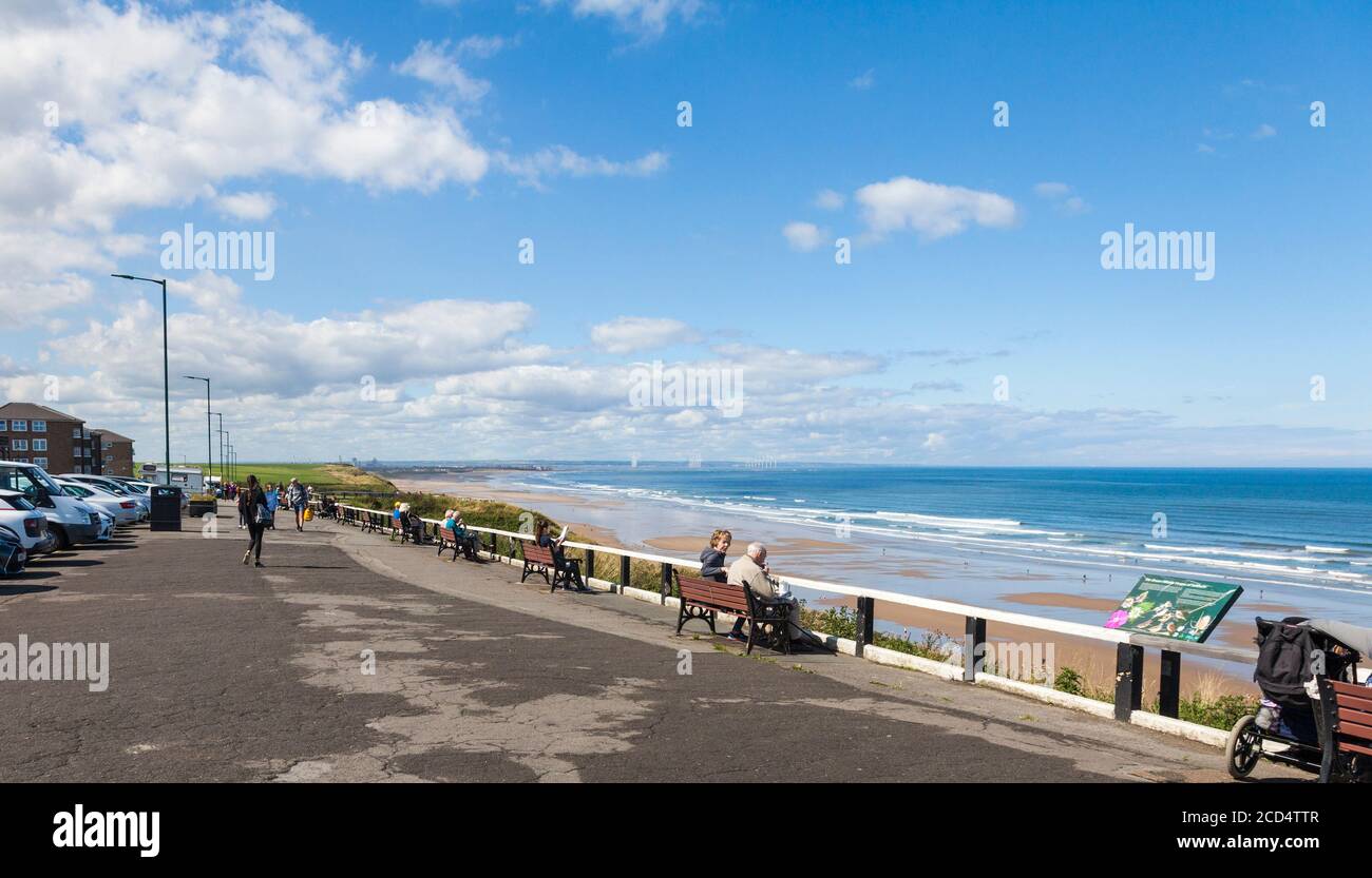 Die Leute saßen auf Bänken an der Promenade und bewunderten die Aussicht In Saltburn by the Sea, England, Großbritannien Stockfoto