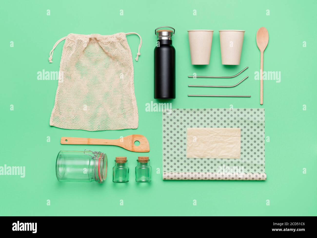 Nachhaltigkeitskonzept Draufsicht. Wiederverwendbare Bio-Einkaufstasche, Kaffeetasse und Bienenwachs Tuch, isoliert auf grünem Hintergrund. Umweltsichere Objekte Stockfoto