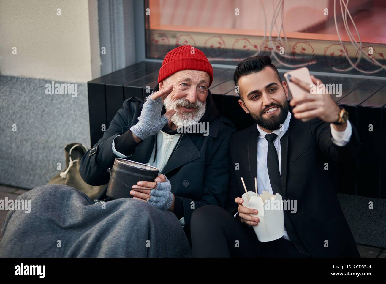 Genial reicher Mann in Kostüm macht Selfie mit kaukasischen Bettler auf der  Straße sitzen, glücklich Stockfotografie - Alamy