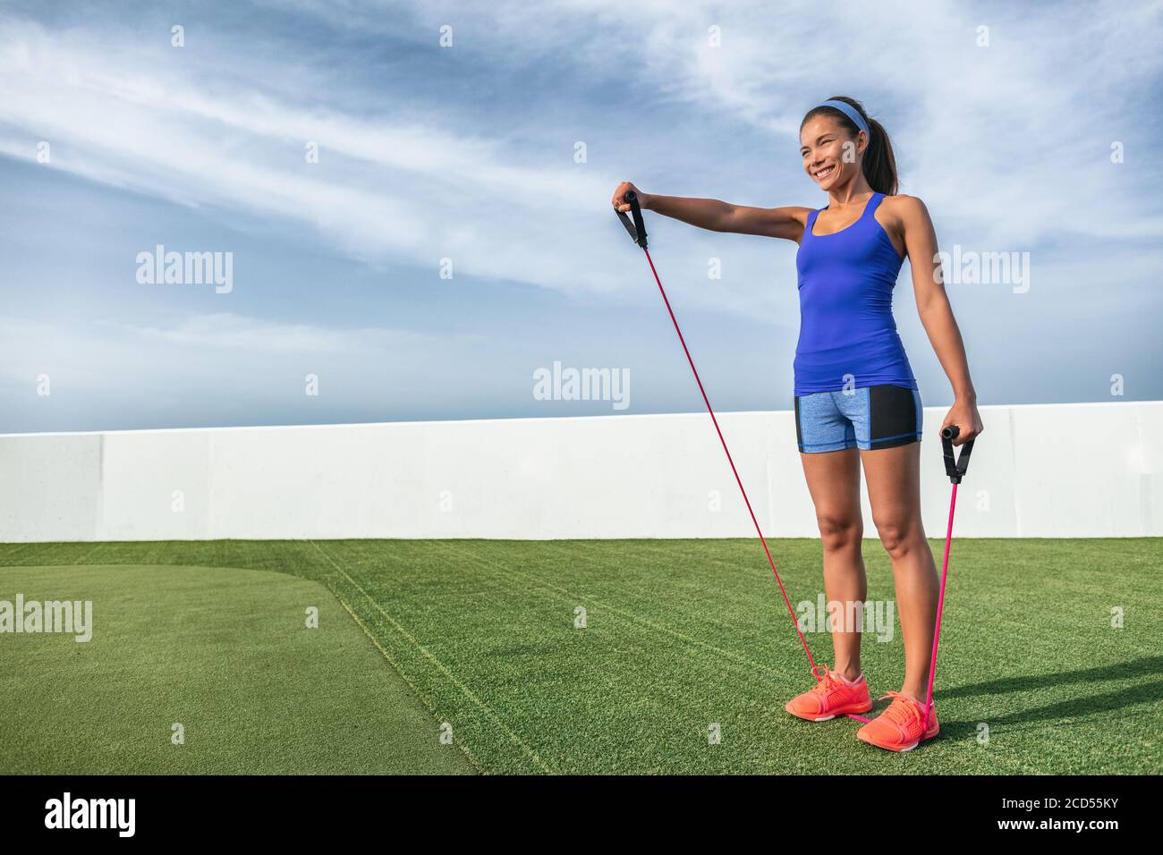 Fitness Widerstandstraining mit Elastikbändern Frau tun elastisches Training draußen im Sommer Hintergrund. Asiatische Mädchen ziehen bis Band für Schulter Stockfoto