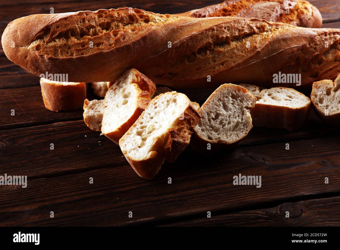 Baguette gebackenes Brot und geschnittenes Baguette auf Holzhintergrund Stockfoto