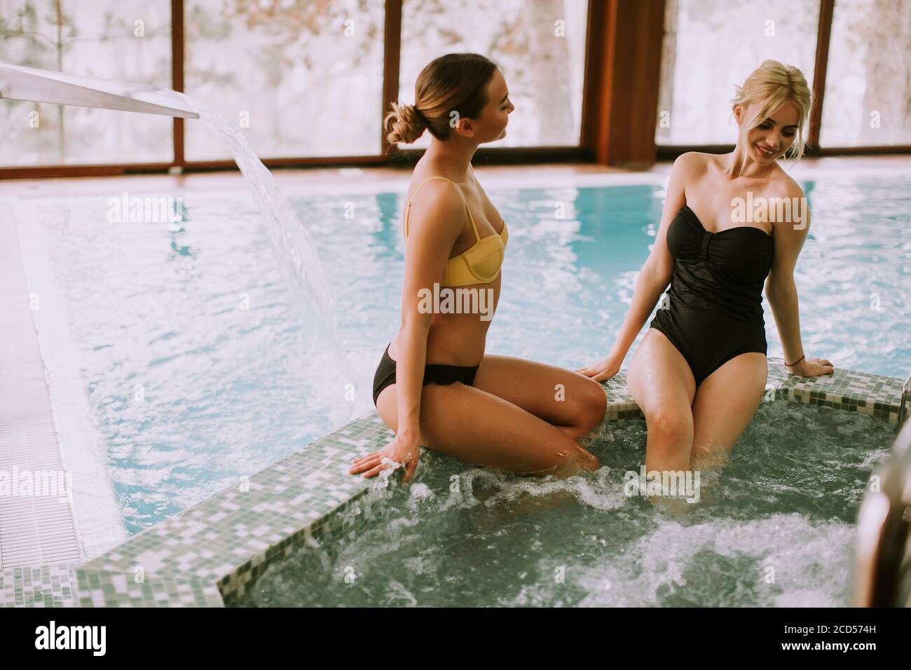 Hübsche junge Frauen sitzen und entspannen an der Whirlpool-Badewanne Stockfoto