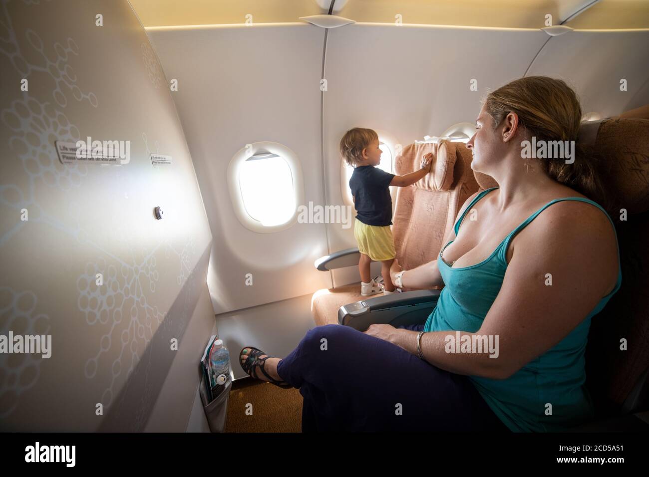 Mama hält ein kleines Kleinkind mit der Hand im Flugzeug. Gefährlich Stockfoto
