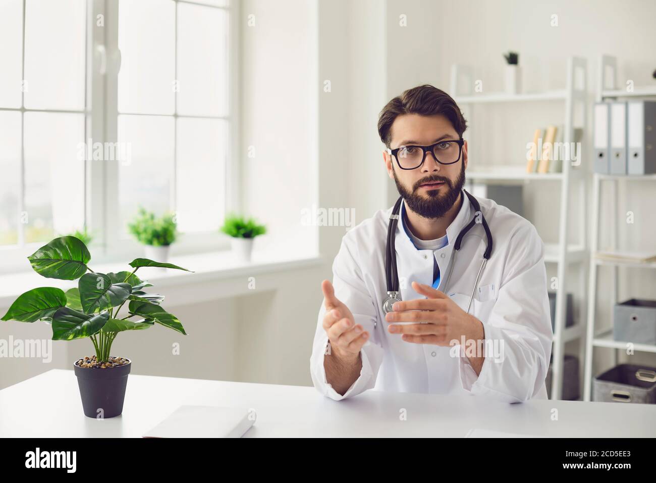 Seriöse Arzt in Brillen sitzen am Tisch in der medizinischen Klinik Stockfoto