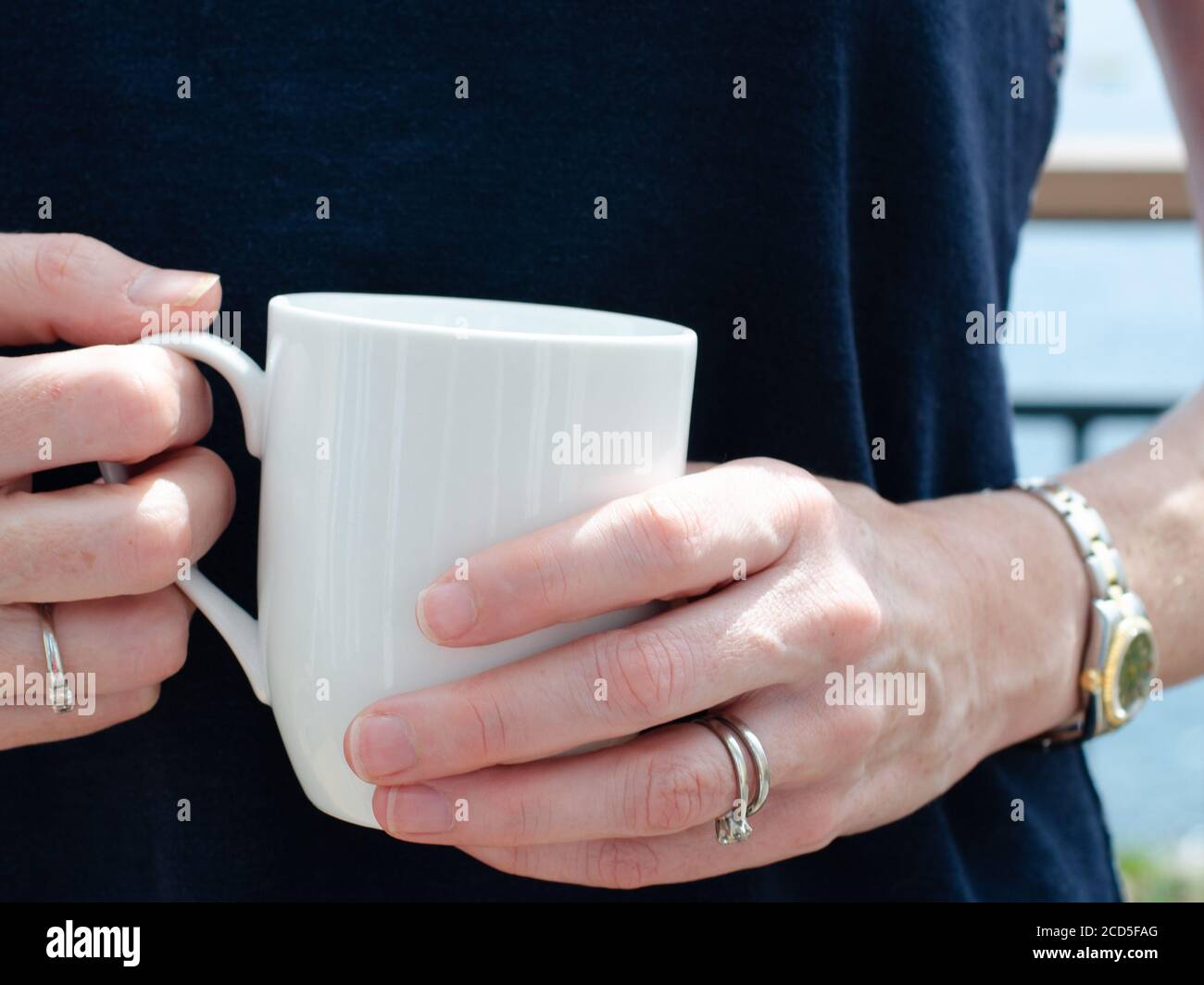 Die Hände der Womans halten einen weißen Becher Tee oder Kaffee Stockfoto