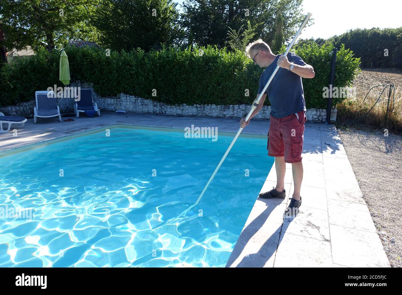 Mann, der einen Pool mit einem Netz putzt Stockfoto