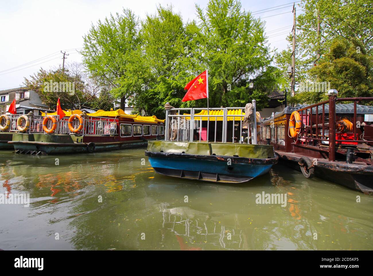 Kanal in Suzhou China mit Booten entlang der angedockt Banken mit Bäumen und Häusern im Hintergrund Stockfoto