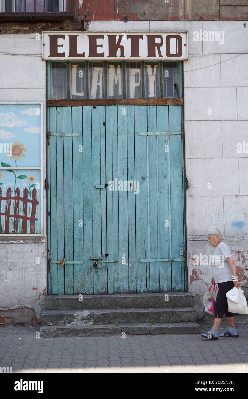 Eine alte Dame, die im Warschauer Praga-Viertel wohnt, mit Einkaufstaschen geht vor einem geschlossenen Elektrogeschäft vorbei. Alltag auf der Straße in der Praga di Stockfoto