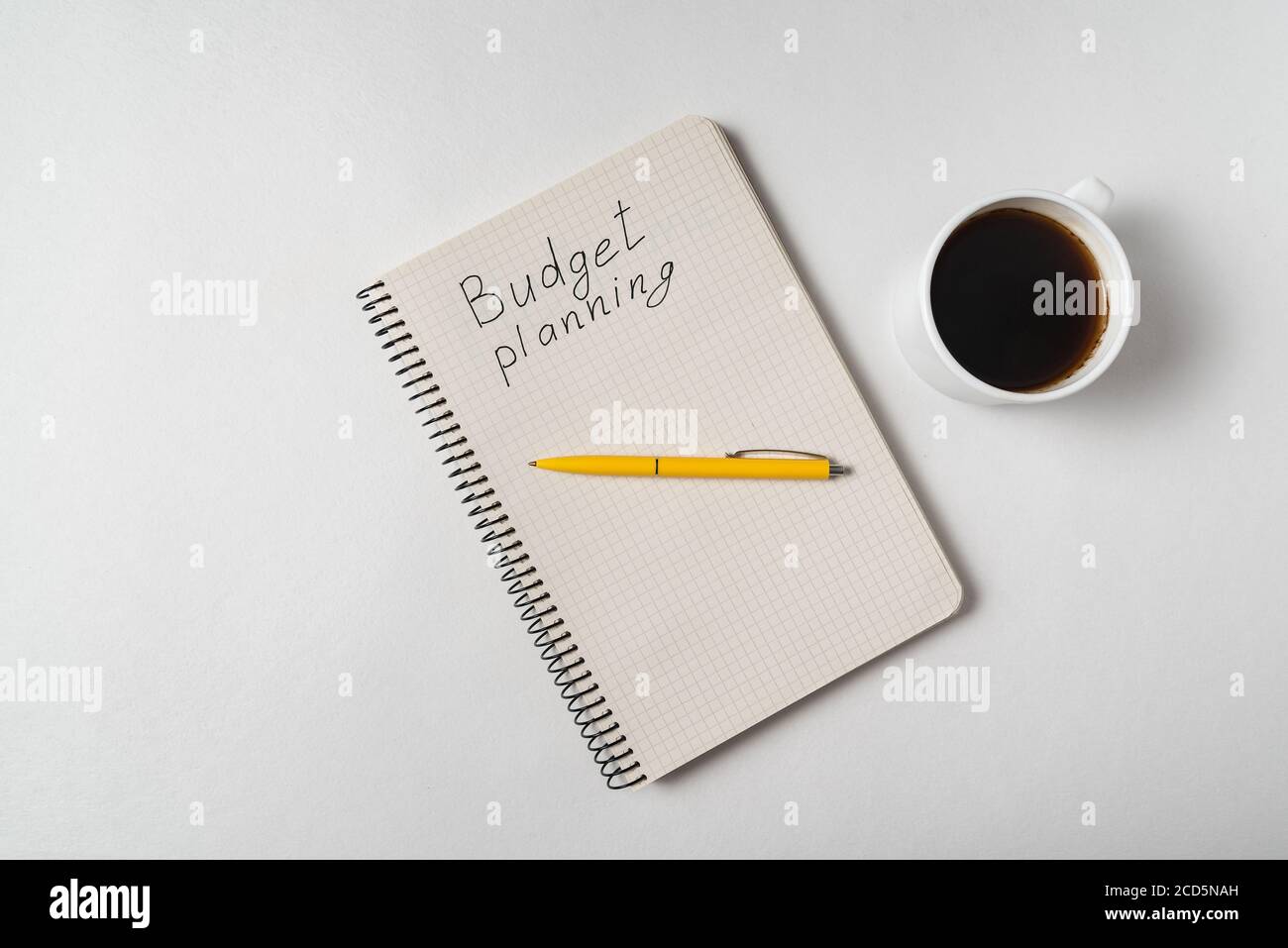 Draufsicht des Notizbuchs mit Budgetplanungstext. Hochzeitsplanung. Notizblock und Kaffee auf weißem Hintergrund Stockfoto