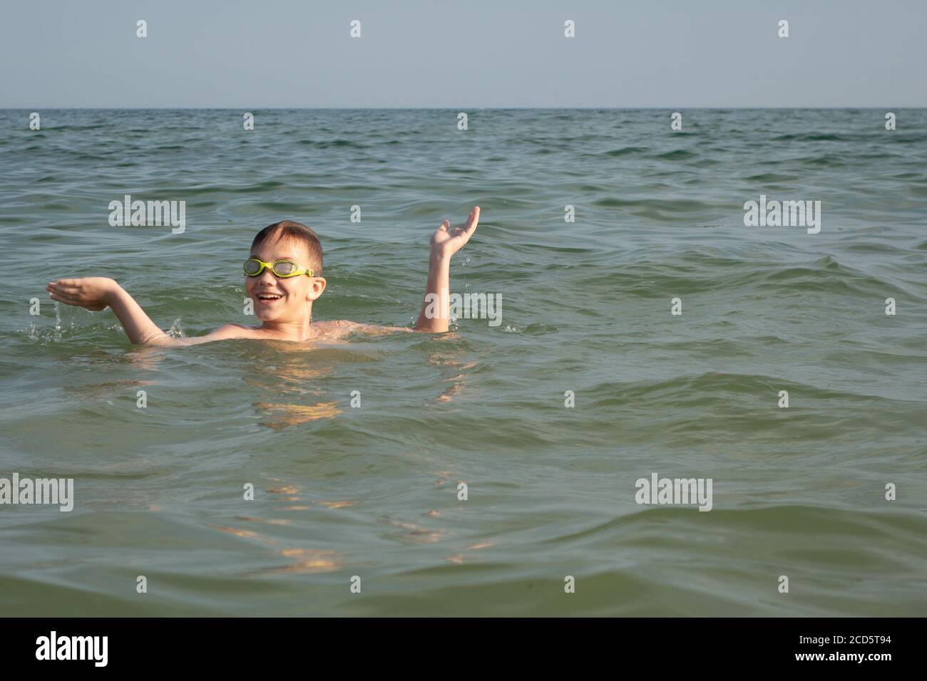 Ein 10-jähriger Junge tauchte aus dem Wasser ins Meer auf und zeigt mit seinen Händen, welche großen Fische er sah. Stockfoto