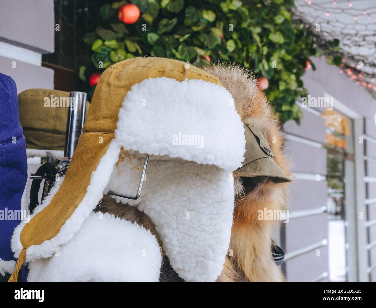 Warmer Pelzhut mit Ohrenklappen, die draußen an einem Kleiderbügel hängen. Verkauf von russischen Souvenirs Stockfoto