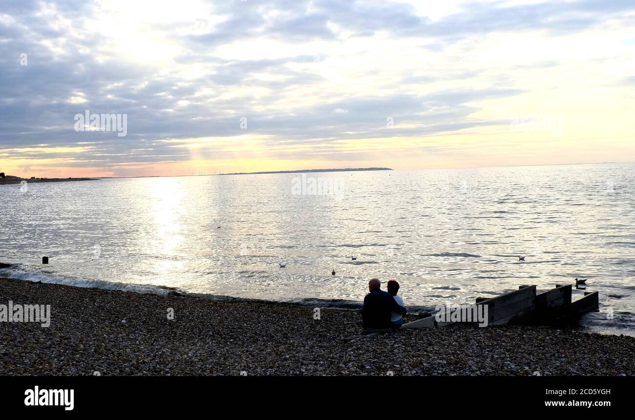 Ein romantisches Paar mittleren Alters, das am hampton-on-Sea Strand bei Sonnenuntergang im Osten sitzt kent uk, august 2020 Stockfoto