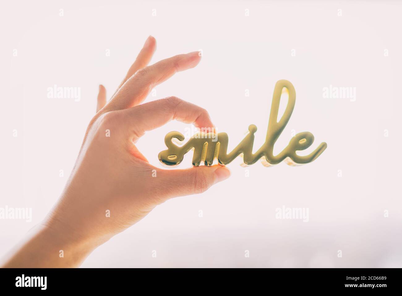 Smile Home Dekor Dekoration Objekt für Zuhause Positivität Wellness. Glückliche Frau Hand halten Skulptur geschrieben LÄCHELN in Gold Messing Metall. Motivierend Stockfoto