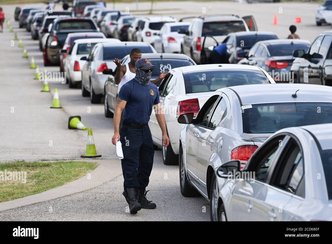 Austin, TX USA 26. August 2020: Die Feuerwehrleute von Austin checken mit Fahrern von Hunderten von Autos aus der Küste von Ost-Texas und dem Südwesten Louisianas ein, während sie in einer Schlange an einem Hurricane Laura Evakuierungszentrum auf dem Circuit of the Americas Rennbahn Parkplatz warten. Fahrer, die früh ankommen, erhalten Gutscheine für Hotelzimmer. Sobald diese ausgelaufen waren, wurden die Fahrer zu anderen Evakuierungszentren in Waco und Dallas geleitet. Laura wird voraussichtlich über Nacht als Sturm der Kategorie 4 landen und verheerende Schäden an der Küste von Texas und Louisiana und im Landesinneren anrichten. Kredit: Bob Daemmrich/Alamy Live Nachrichten Stockfoto