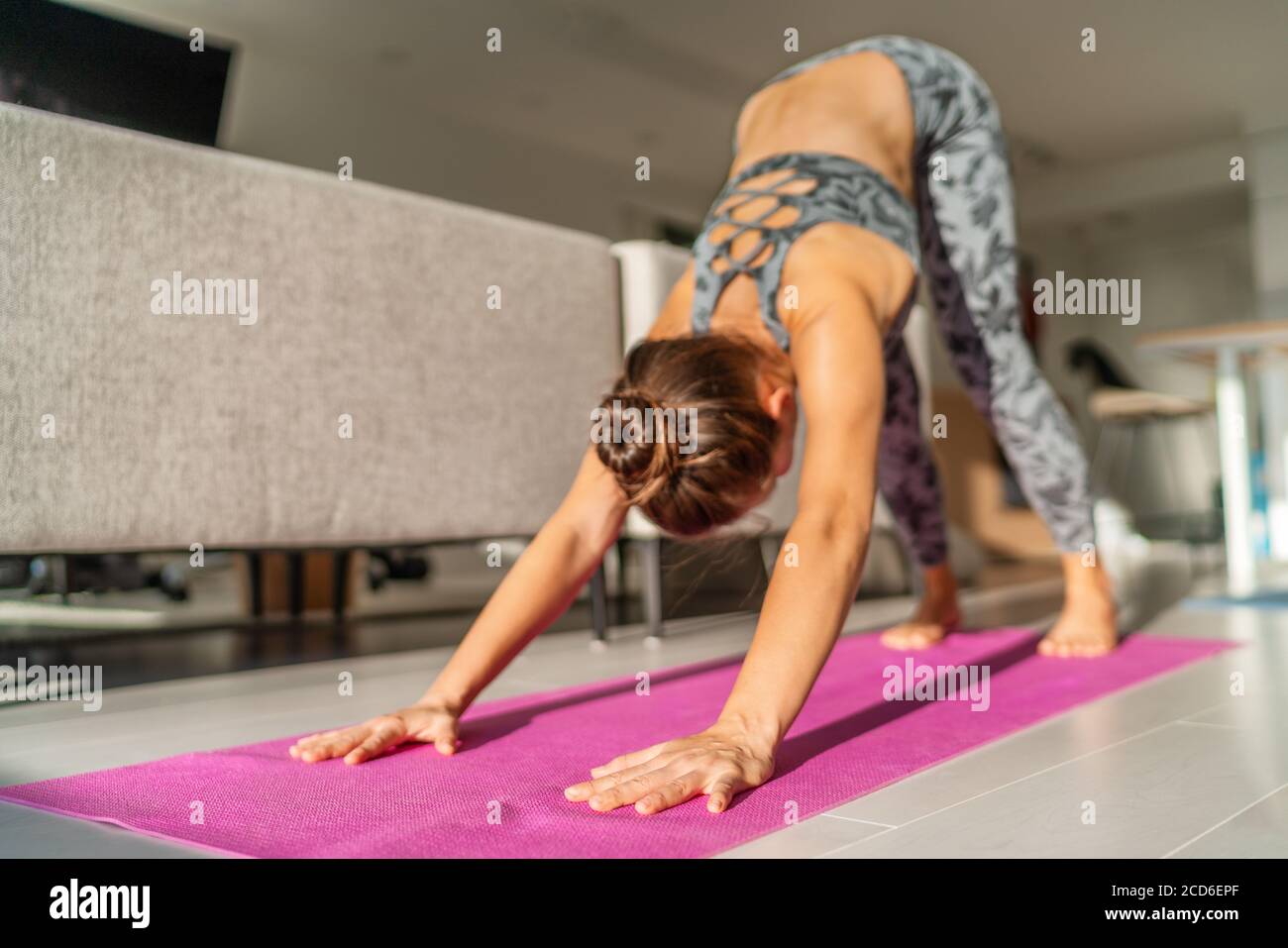 Yoga Morgen Frau Stretching in nach unten Hund Pose im Wohnzimmer zu Hause Training drinnen. Aufwärmen Sonne Anrede Routine auf Trainingsmatte. Fitness Stockfoto