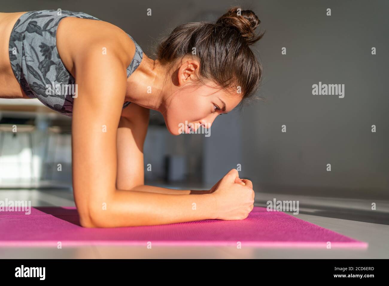 Heimfitness, Training zu Hause Mädchen Training drinnen Boden Übungen auf Übungsmatte in Wohnung Wohnung. Asiatische Frau planking tun Bodyweight Yoga Stockfoto