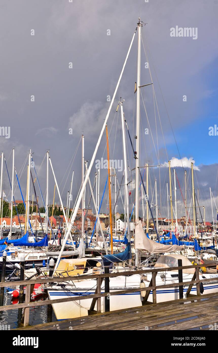 Viele schöne Segelboote mit hohen Stöcken in einem kleinen jachthafen bei Flensburg/Deutschland vor bewölktem und windigem Himmel Stockfoto