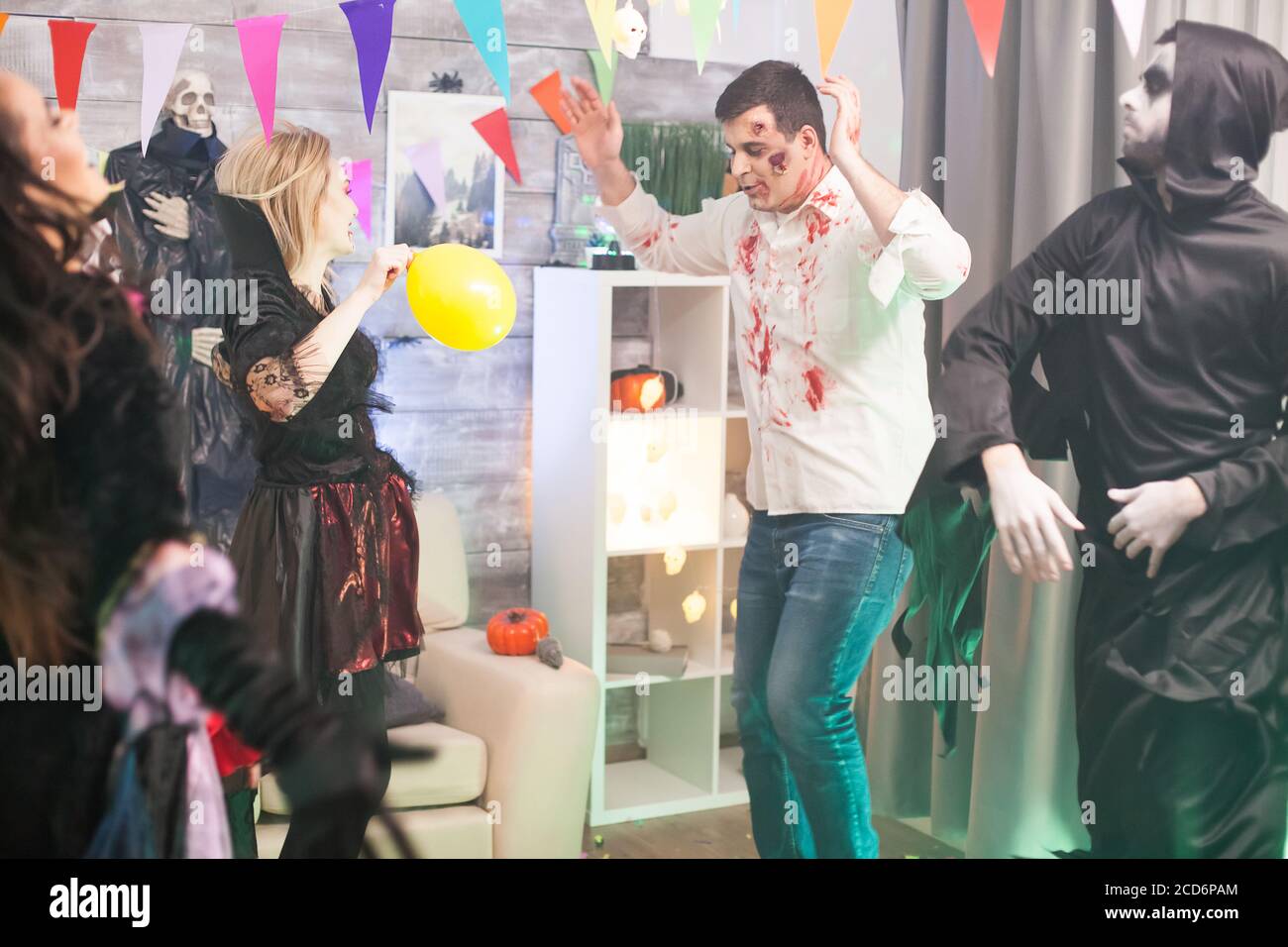 Blutiger Zombie und grimmiger Reaper tanzen bei halloween mit den Händen nach oben. Stockfoto