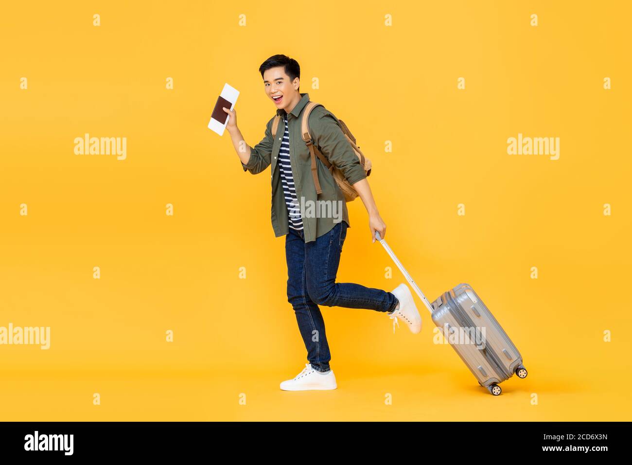In voller Länge Porträt von fröhlichen jungen lächelnden Touristen asiatischen Mann Gehen Sie mit Gepäck und zeigen Sie den Pass mit Ticket in Isoliertes Studio yel Stockfoto In voller Länge Porträt von fröhlichen jungen lächelnden Touristen asiatischen Mann Gehen Sie mit Gepäck und zeigen Sie den Pass mit Ticket in Isoliertes Studio yel Stockfoto