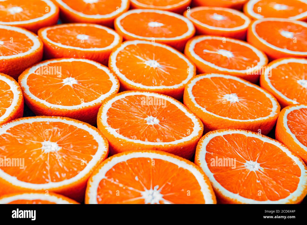 Rote Orangen oder Grapefruits werden auf schwarzem Hintergrund halbiert. Stockfoto