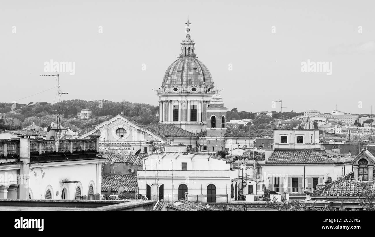 Skyline von Rom mit alten bunten Häusern und Dachterrassen an sonnigen Tagen. Kuppel der Basilika San Carlo al Corso auf dem Hintergrund. Rom, Italien. Schwarzweiß-Bild. Stockfoto