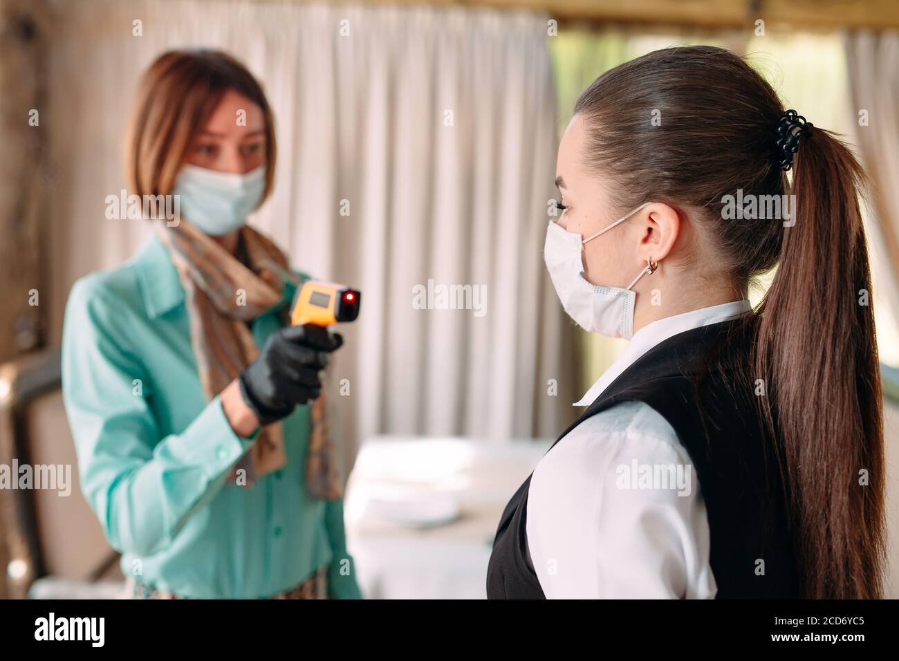 Der Manager eines Restaurants oder Hotels überprüft die Körpertemperatur des Personals mit einem Wärmebildgerät. Stockfoto