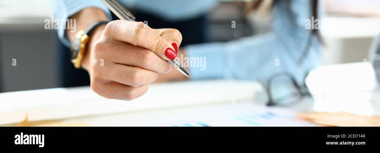 Frau im Büro hält einen Stift in ihrer Hand über dem Diagramm Stockfoto