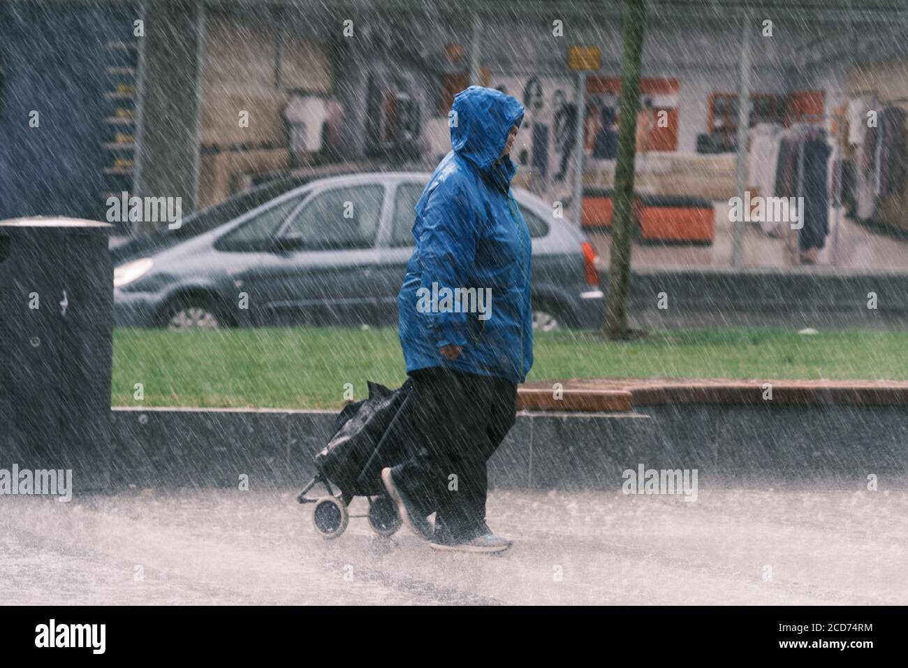 UK Wetter: Lady mit Shopping Trolley in heftigen Regenschauer erwischt, Preston, UK. Stockfoto