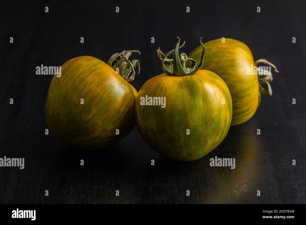 Grüne Zebratomaten auf schwarzem Tisch. Stockfoto