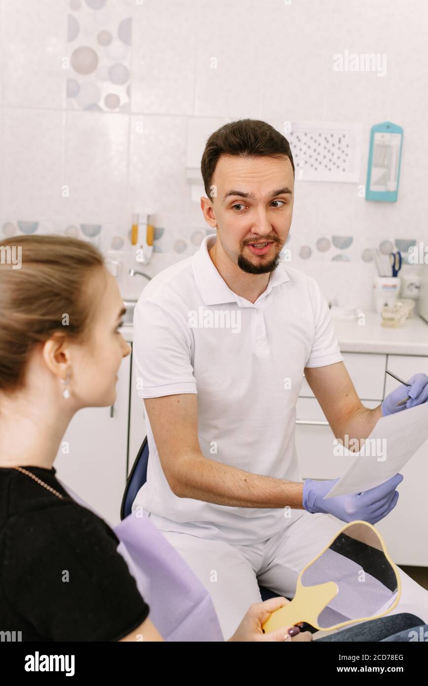 Der Zahnarzt zeigt einer niedlichen Frau eine Röntgenaufnahme der Zähne des Patienten. Empfang beim Zahnarzt. Stockfoto