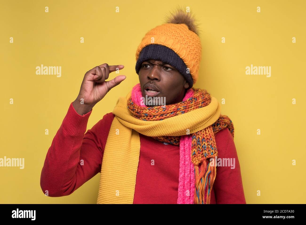Enttäuschter afrikanischer Mann in Winterkleidung mit kleiner Größe. Stockfoto