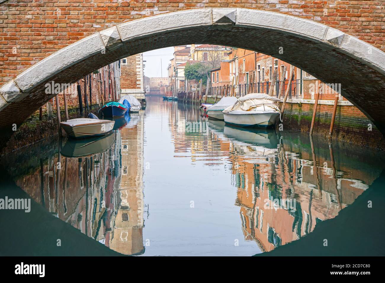 Typisch venezianische Landschaft mit einer Brücke und Booten angedockt Der malerische Kanal mit Wasserspiegelungen Stockfoto