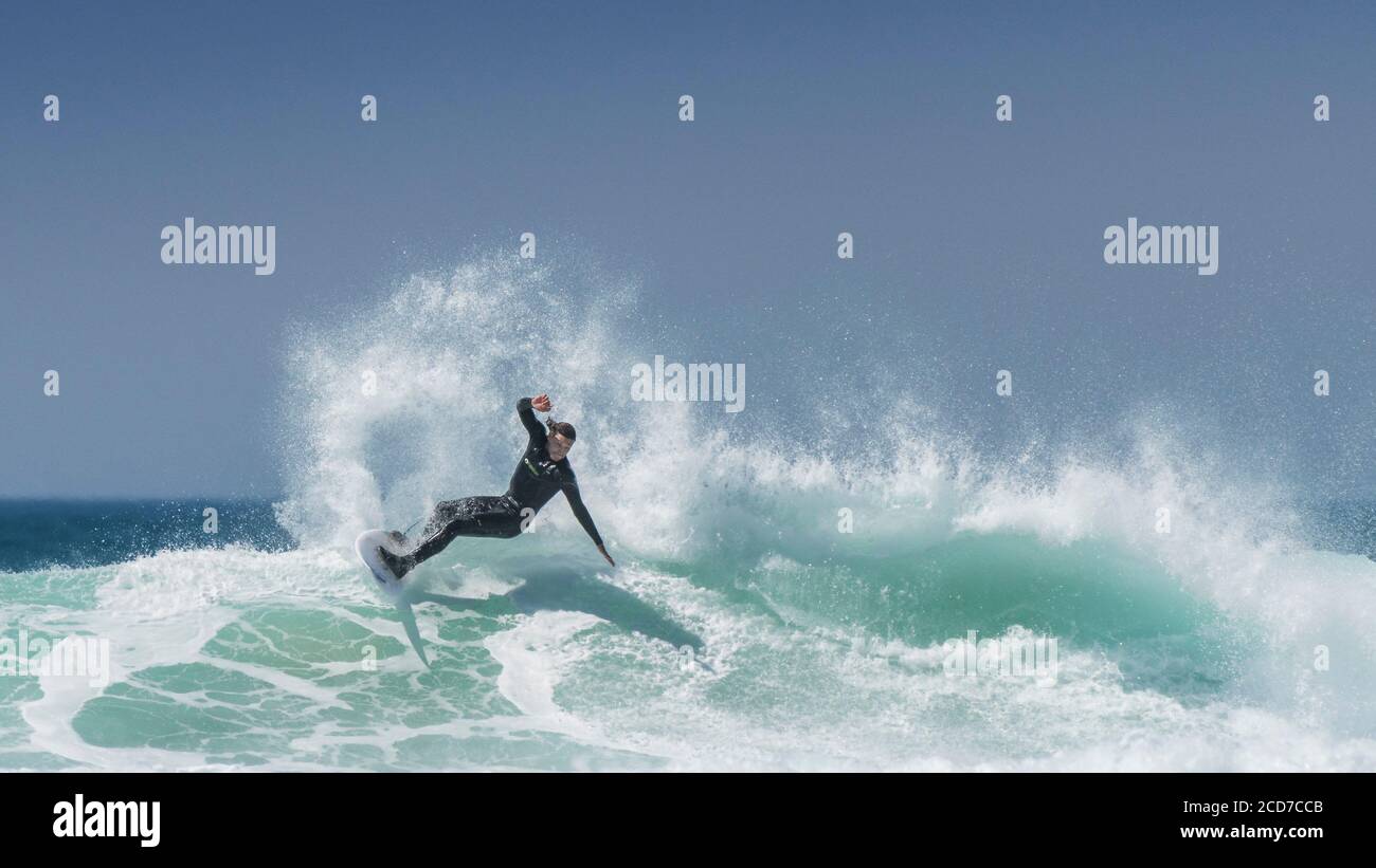 Ein Panoramabild spektakulärer Surfaktion, während ein Surfer eine Welle am Fistral in Newquay in Cornwall reitet. Stockfoto