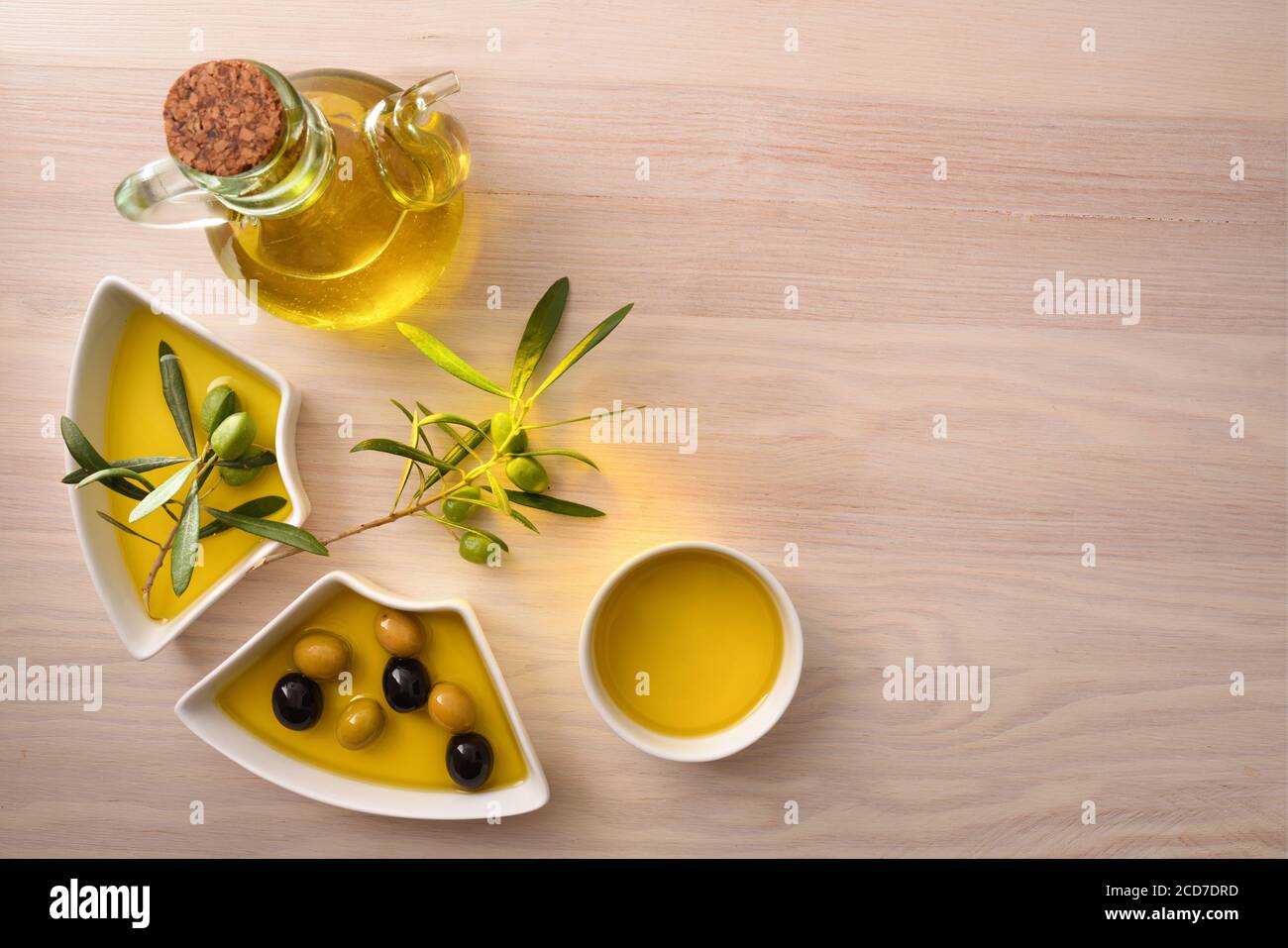 Olivenöl in Behältern mit Oliven auf hölzerner Küchenbank. Draufsicht. Stockfoto